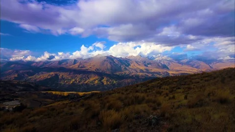 Fluffy clouds moving over mountain and landscape Stock Footage 77444800