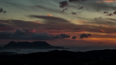 Fluffy clouds moving over sea and mountain during sunset Stock Footage 77548906