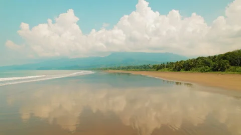 Fluffy clouds reflect on wet sand beach in Marino Ballena National Park Costa Stock Footage 343382599