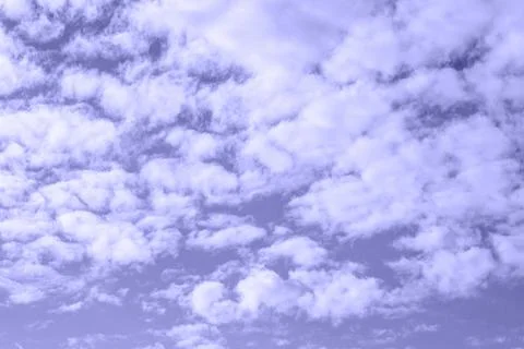 Fluffy clouds on sky on a summer day toned in trendy Very Peri. Stock Photos
