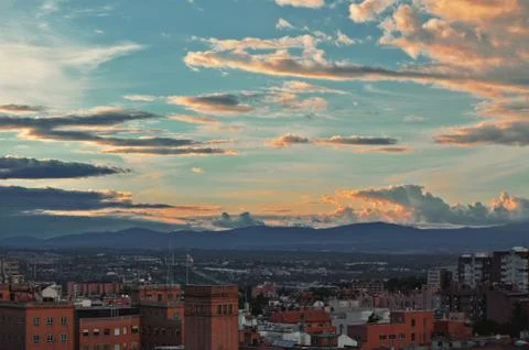 Fluffy clouds at sunset over the evening city Stock Photos