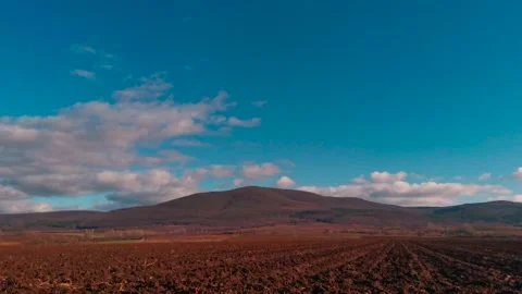 Fluffy clouds time lapse over a plough field Stock Footage 145730395
