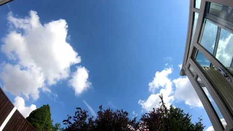 Fluffy cumulus clouds moving slowly through a bright, clear blue sky, time-lapse 스톡 동영상 220141946