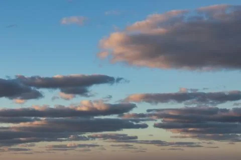Fluffy flat clouds against a blue sky during golden hour Foto stock