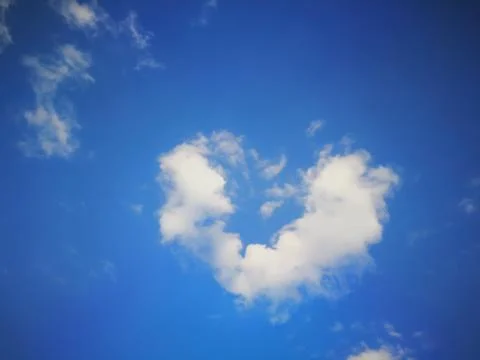Fluffy heart shape clouds in blue sky for Valentine's background Stock Photos