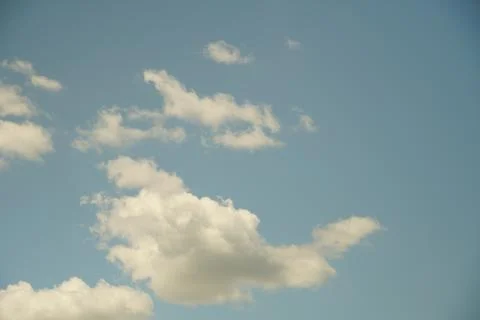 Fluffy orange clouds in a blue sky illuminated by the light of the setting su Stock Photos