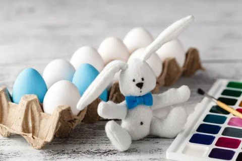 Fluffy rabbit in basket with Easter eggs Stock Photos
