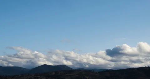 Fluffy Rolling Clouds Blue Sky Timelapse Over Mountains 4K Stock Footage 113941557