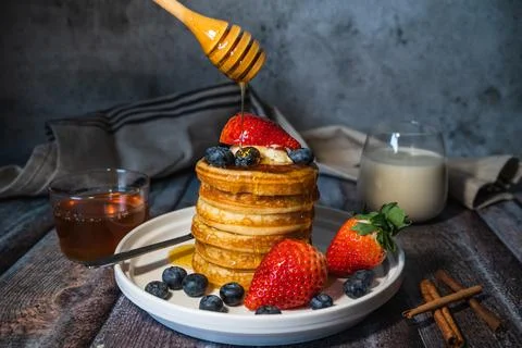 A fluffy soft pancake stack with pouring maple syrup from stick, fresh bluebe Stock Photos