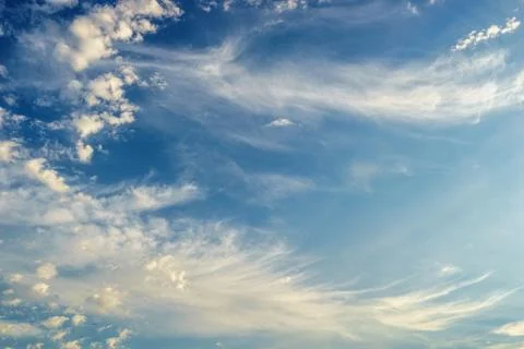 Fluffy soft scattered white clouds on a late afternoon blue sky Stock Photos