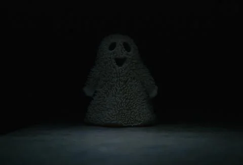 Fluffy toy smiling ghost peeks out of the darkness Stock-Fotos