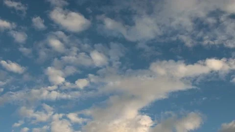 Fluffy white and grey clouds move slowly diagonally through a bright blue sky.  Stock Footage 138662119