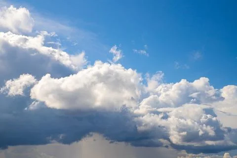 Fluffy white cloud and blue sky above. Thundercloud and rain below. Divine Stock Photos