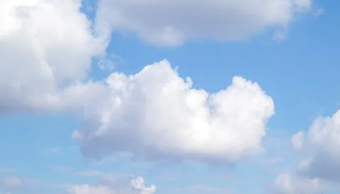 Fluffy white cloud floating in a bright blue sky over a calm summer atmosphere Stock Photos