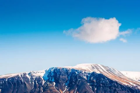 Fluffy white cloud over a mountain top Stock Photos