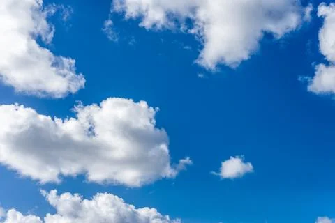 Fluffy white clouds against a bright, colorful blue sky Фото