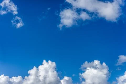 Fluffy white clouds against a bright, colorful blue sky Stock Photos