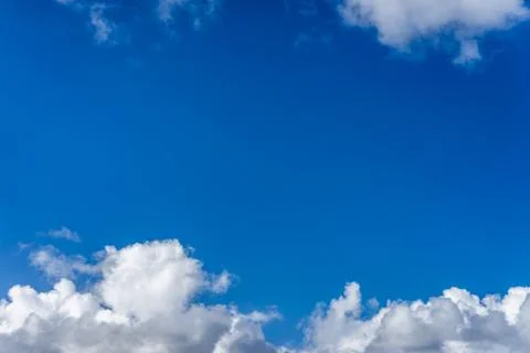Fluffy white clouds against a bright, colorful blue sky Stock Photos