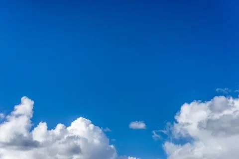 Fluffy white clouds against a bright, colorful blue sky Stock Photos