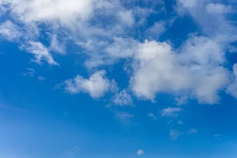 Fluffy white clouds against a bright, colorful blue sky Stock Photos