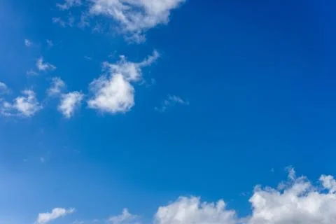 Fluffy white clouds against a bright, colorful blue sky Stock Photos