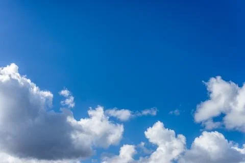 Fluffy white clouds against a bright, colorful blue sky Stock Photos