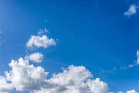 Fluffy white clouds against a bright, colorful blue sky Stock Photos