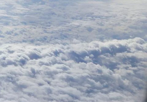 Fluffy white clouds from airplane window Stock Photos