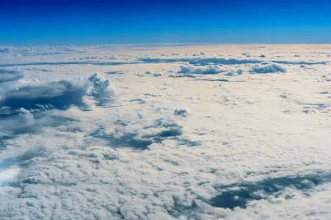 Fluffy white clouds and blue sky seen from airplane. Stock Photos