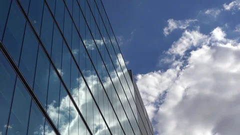 Fluffy white clouds on blue sky mirrored in modern glass building Stock Footage 79844929