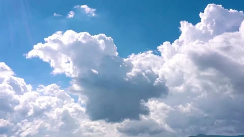 Fluffy white clouds in a bright blue sky, cloudscape over a mountain horizon Stock Footage 339590447