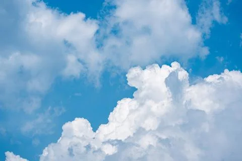 Fluffy white clouds in a bright blue daytime sky Stock Photos