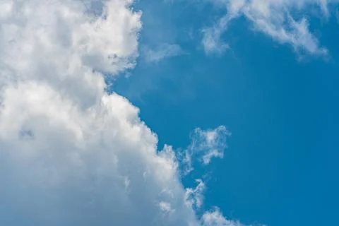 Fluffy white clouds in a bright blue daytime sky Stock Photos