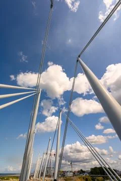 Fluffy white clouds in a deep blue sky through the metal posts of the Passere Stock Photos