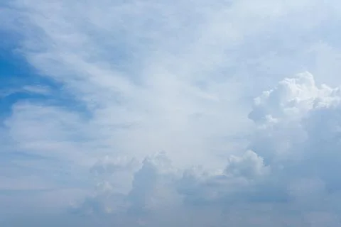Fluffy white clouds drift across a vibrant blue sky during a bright sunny Stock Photos