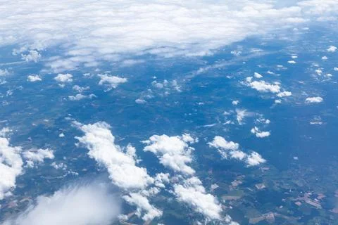 Fluffy white clouds drift below against vast sky Stock Photos