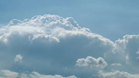 Fluffy white clouds drift gracefully against a bright blue sky adorned with sere Stockfoto's