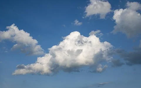 Fluffy White Clouds Drifting Across a Bright Blue Sky in Midday Sun Stock Photos