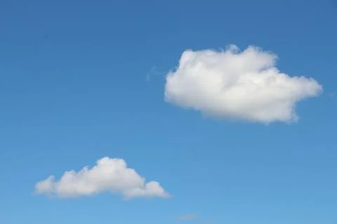 Fluffy white clouds drifting in a clear blue sky during a sunny afternoon Foto stock