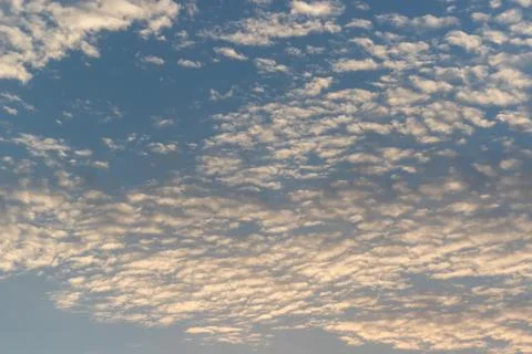 Fluffy white clouds float across a bright blue sky during a calm and peacef.. Stock Photos