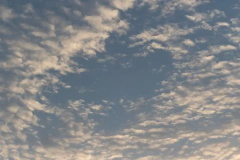Fluffy white clouds float across a bright blue sky during a beautiful sunny.. Stock-Fotos