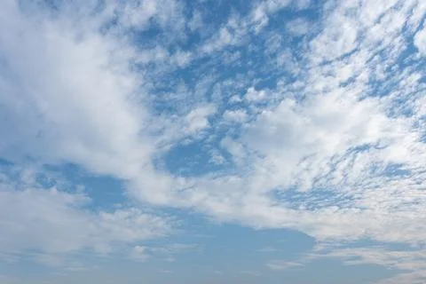 Fluffy white clouds float across a bright blue sky during a sunny day nature Stock Photos