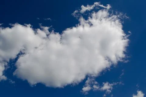 Fluffy white clouds float in a clear blue sky. The scene captures a serene .. Stock Photos