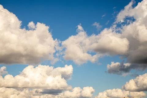 Fluffy white clouds float gracefully in a blue sky during mid-afternoon Stock Photos