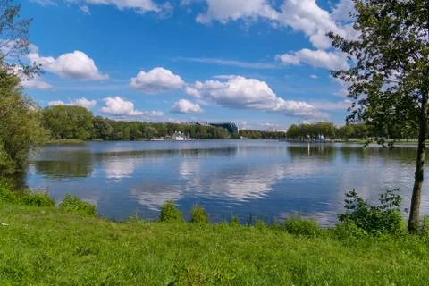 Fluffy white clouds float through the blue sky over the calm flat water Stock Photos