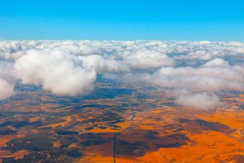 Fluffy white clouds floating above landscape of orange earth Foto stock