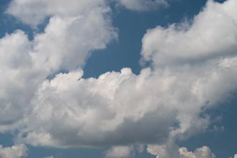 Fluffy white clouds floating against a bright blue sky on a sunny day Stock Photos