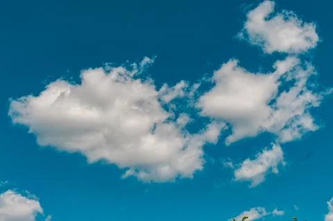 Fluffy white clouds floating in a vibrant blue summer sky Stock Photos