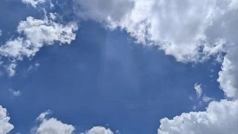 Fluffy white clouds frame a bright, deep blue sky, creating a natural windo.. Foto stock