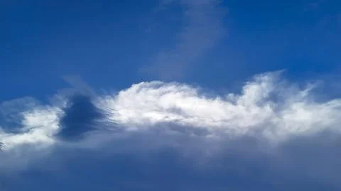 Fluffy white clouds gently drift against a deep blue sky, creating a serene Foto stock